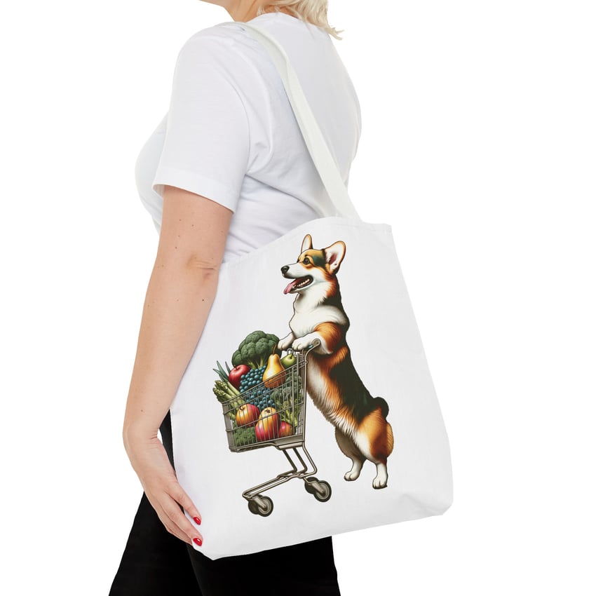 Woman holds tote with colorful corgi and fruit design, on white background.