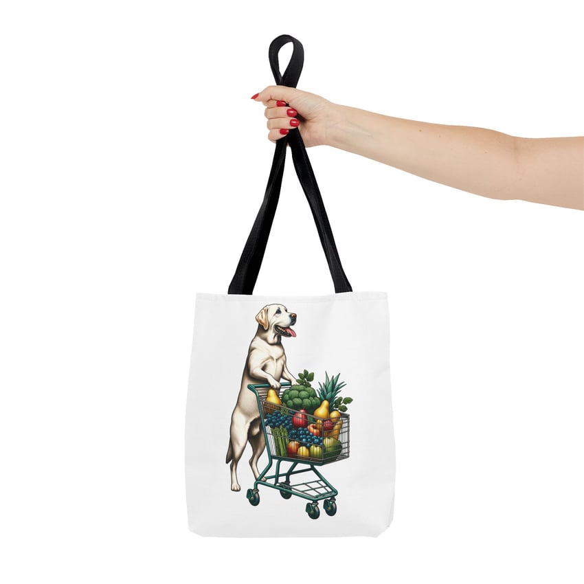 Red-nailed hand holds tote with cartoon dog and vibrant shopping cart illustration.