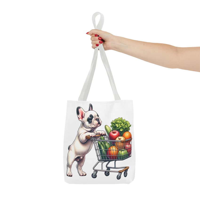 White tote with French Bulldog and grocery cart illustration, held by hand with red nails.